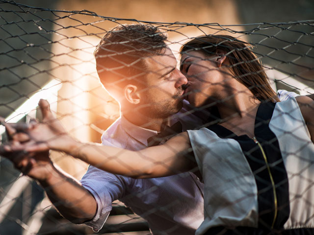 フェンスでキスするカップル