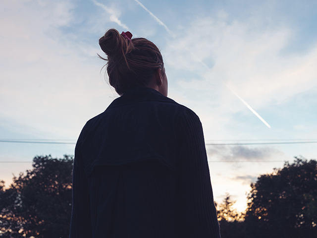 The silhouette of a young woman looking at sunset